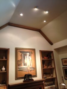Vaulted ceiling with recessed lighting over built-in display shelves